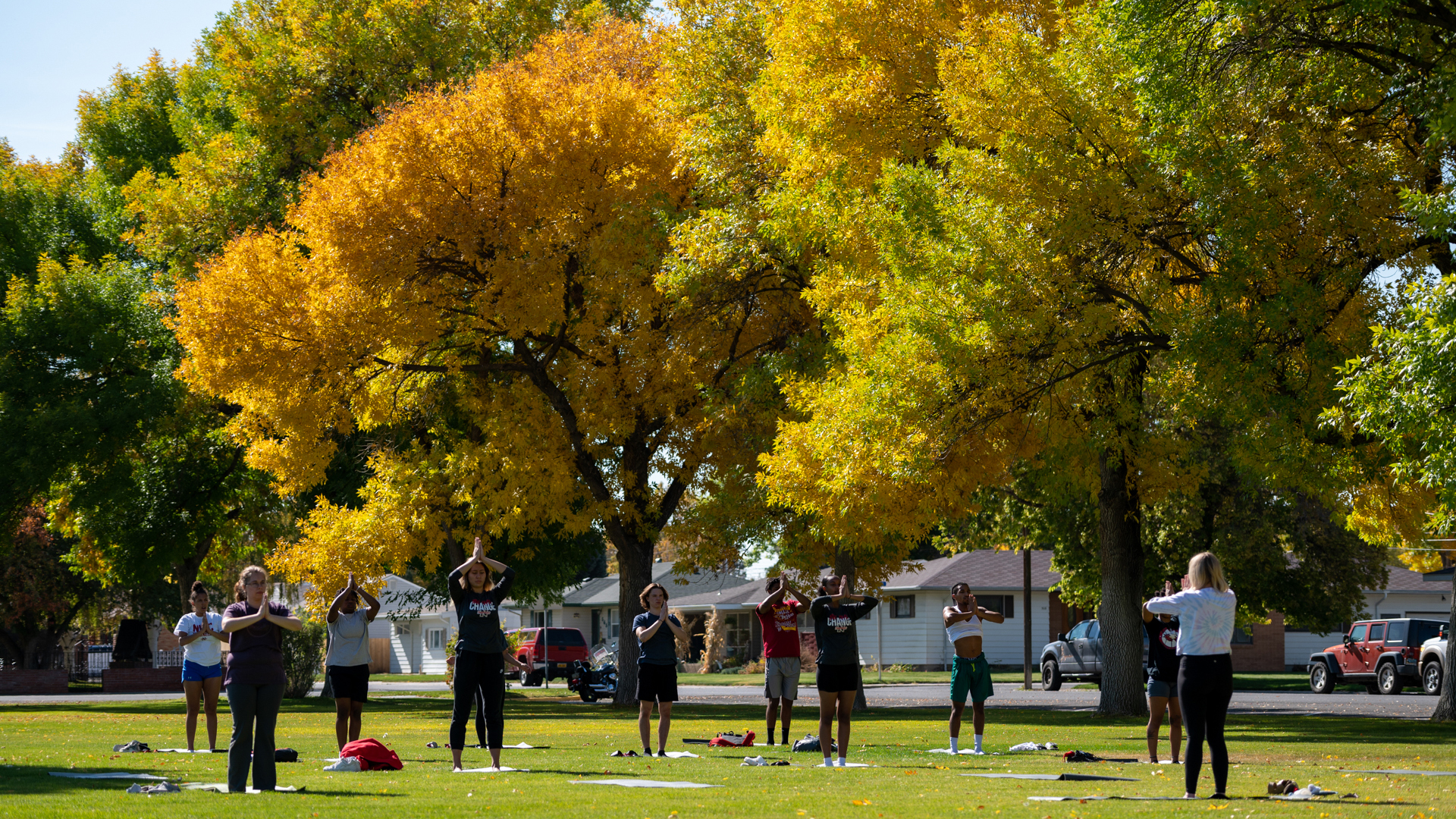 People doing yoga on a campus lawn with bright fall colors