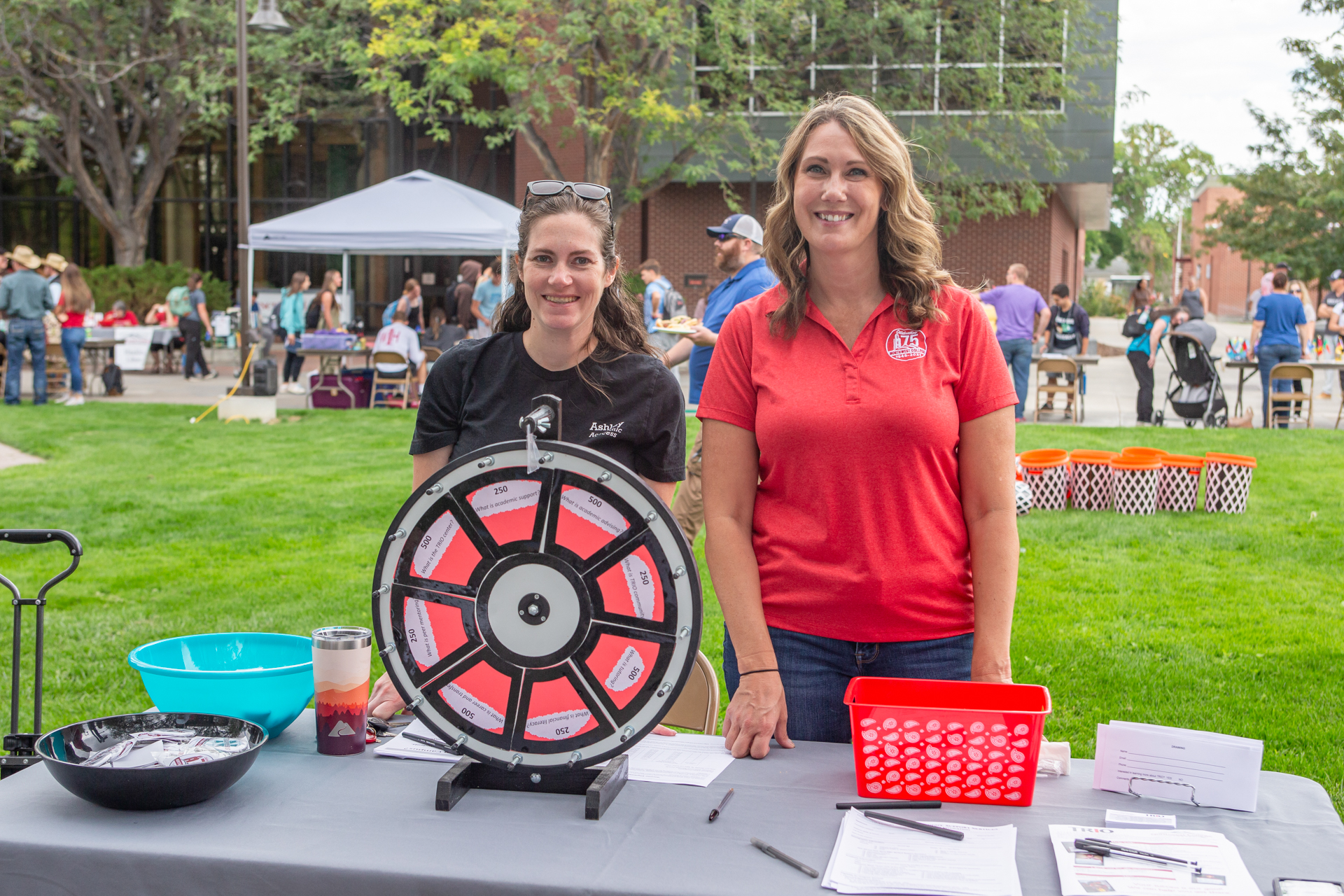 Two Trio staff members in the campus mall at a table